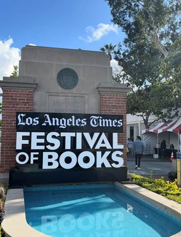Image of the Los Angeles Times Festival of Books signage in front of the University of Southern California fountain with blue skies in the background.